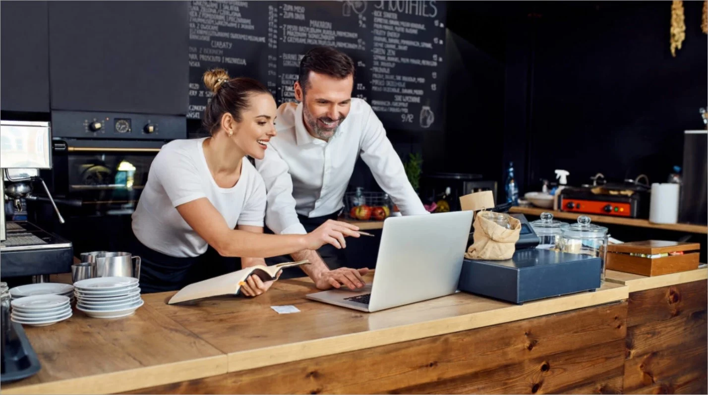 A restaurant owner checks social media marketing metrics on a laptop.